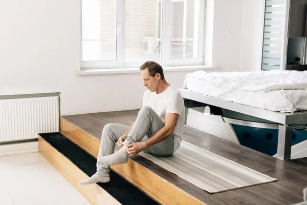 Hombre Guapo Usando Calcetín Mientras Está Sentado Casa —  Fotos de Stock