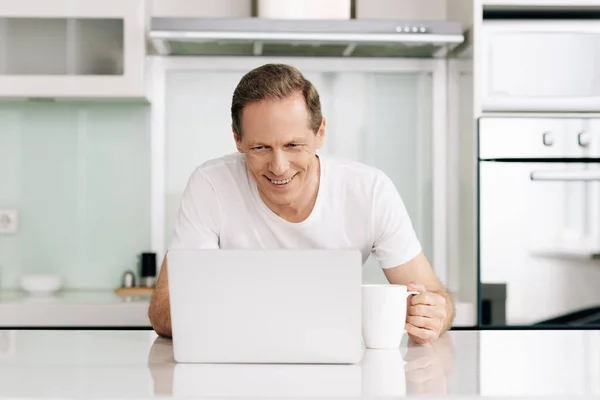 Fröhliche Freiberuflerin Blickt Auf Laptop Und Hält Tasse Hause — Stockfoto