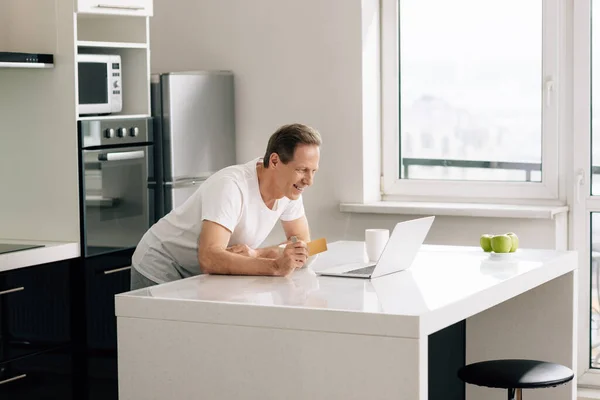 Fröhlicher Mann Mit Kreditkarte Beim Blick Auf Laptop — Stockfoto