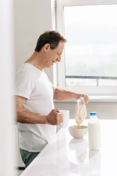 Vista Laterale Felice Uomo Versando Cornflakes Ciotola Vicino Bottiglia Con — Foto Stock