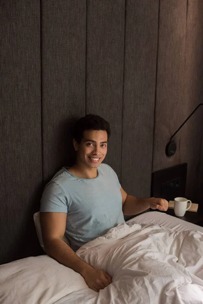 Gülümseyen Melez Irk Adamı Kendini Yalnız Hissederek Yatakta Oturuyor — Stok fotoğraf
