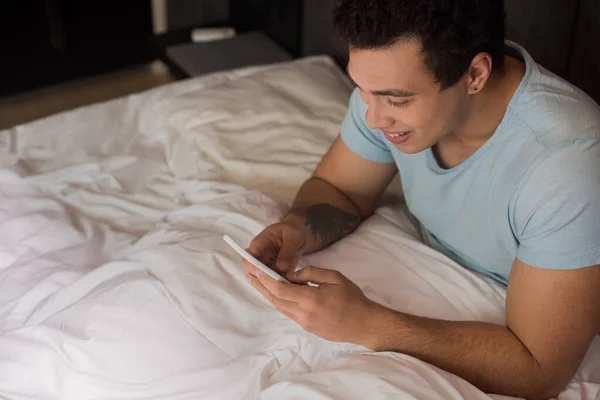 Sonriente Joven Hombre Raza Mixta Usando Smartphone Cama Cuarentena — Foto de Stock