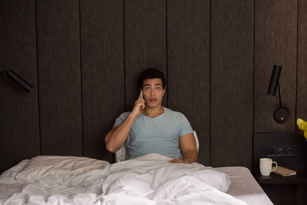 Όμορφος Έκπληκτος Μικτή Φυλή Άνθρωπος Μιλάει Στο Smartphone Στο Κρεβάτι — Φωτογραφία Αρχείου