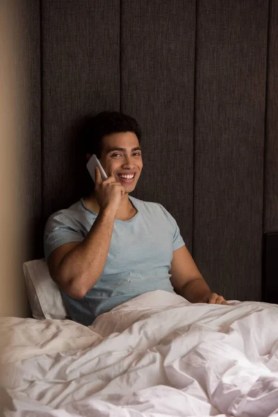 Χαμογελαστός Άνθρωπος Μικτή Φυλή Μιλάμε Στο Smartphone Στο Κρεβάτι Καραντίνα — Φωτογραφία Αρχείου