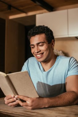 Karantina sırasında mutfakta kitap okuyan mutlu bir ırk adamı.