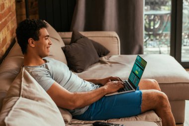Mutlu karışık ırk adamı kendini tecrit sırasında SportsBet web sitesinde dinleniyor ve bilgisayar kullanıyor.