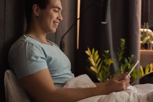 Sorrindo Bonito Homem Raça Mista Usando Tablet Digital Cama Durante — Fotografia de Stock