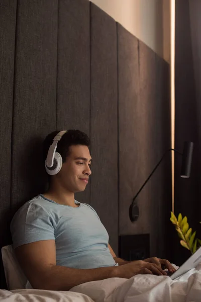 Racial Man Listening Music Headphones Laptop Bed Quarantine — Stock Photo, Image