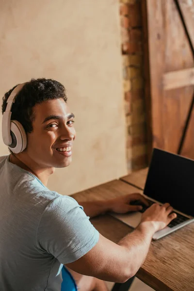 Sorridente Uomo Razziale Ascoltare Musica Con Cuffie Utilizzando Computer Portatile — Foto Stock