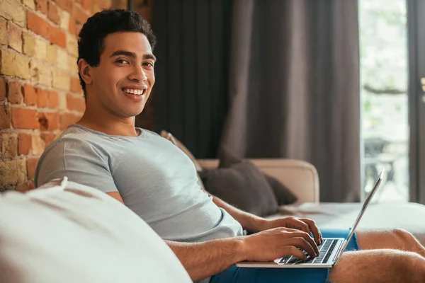 Uomo Razza Mista Sorridente Agghiacciante Con Computer Portatile Sul Divano — Foto Stock