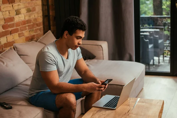 Apuesto Freelancer Raza Mixta Trabajando Con Smartphone Portátil Sofá Durante — Foto de Stock