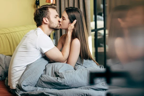 双目紧闭的英俊男人在卧室里亲吻迷人而性感的女朋友的选择性焦点 — 图库照片