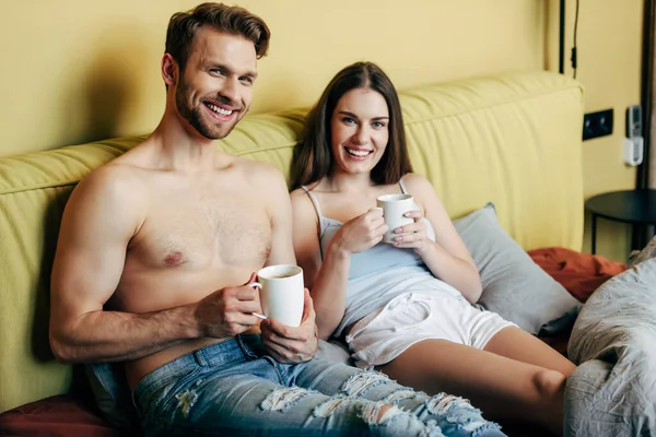 Feliz Hombre Musculoso Mujer Alegre Mirando Cámara Mientras Sostiene Tazas — Foto de Stock