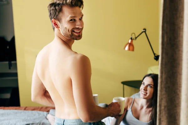 Selective Focus Shirtless Man Smiling While Holding Cups Girl Bedroom — Stock Photo, Image