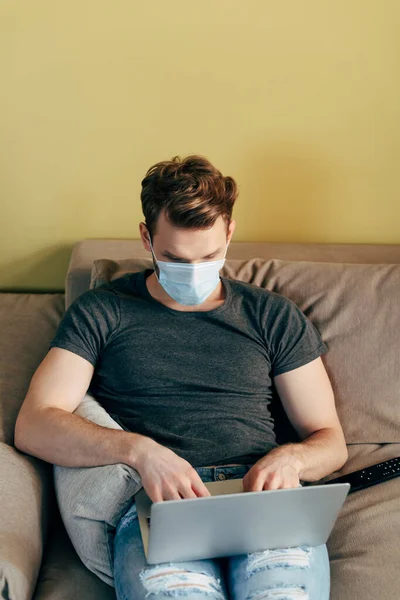 医療用マスクのフリーランサーは自宅のノートパソコンで — ストック写真