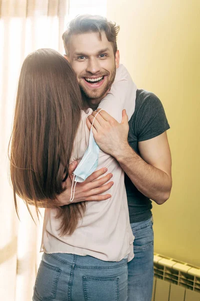 Vista Posterior Chica Abrazando Alegre Novio Con Máscara Médica Mano — Foto de Stock