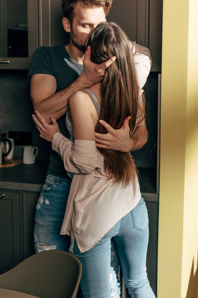 Вид сзади женщины, целующейся с бородатым мужчиной дома
 