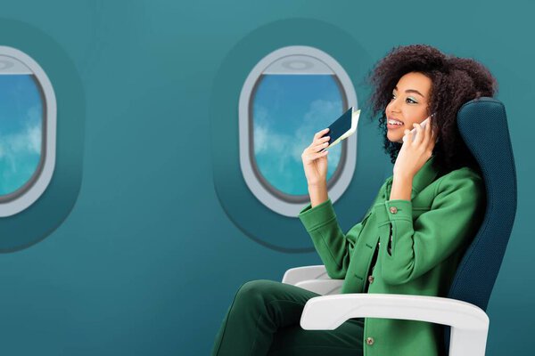 smiling african american woman talking on smartphone and holding passport with air ticket on green background with portholes