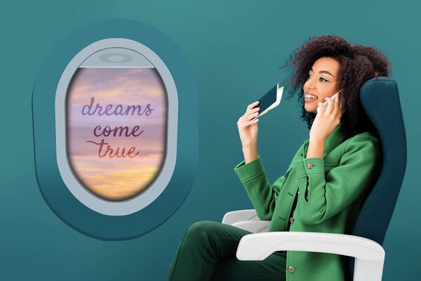 улыбающаяся африканская американка разговаривает по смартфону и держит паспорт с авиабилетом на зеленом фоне с иллюминатором
