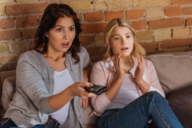 Evde film izleyen heyecanlı anne ve kızın seçici odağı 