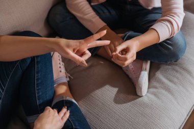 Kanepede taş kağıt makas oynayan anne ve kızın kesikli görüntüsü 