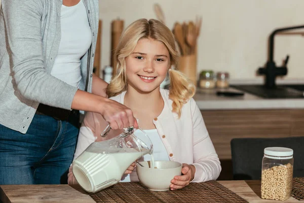 Kid Smiling Camera While Mother Pouring Milk Cereals Kitchen — Stock Photo, Image