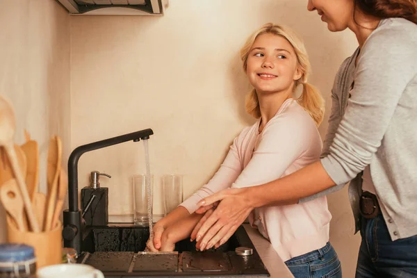 Foco Seletivo Criança Sorridente Lavar Mãos Perto Mãe Cozinha — Fotografia de Stock