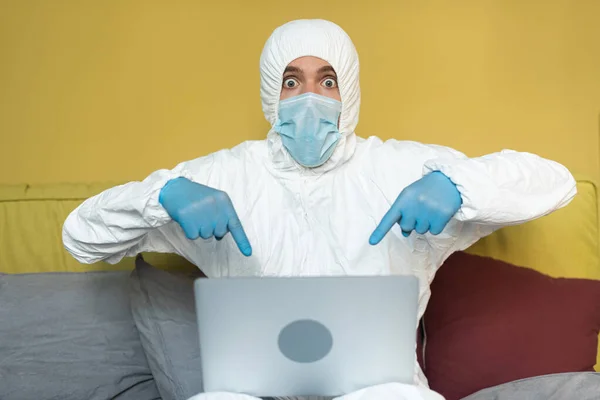 Geschokt Man Hazmat Pak Wijzend Met Vingers Laptop Bed — Stockfoto