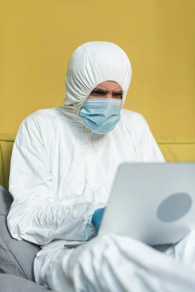 Selektivní Zaměření Muže Ochranném Obleku Lékařské Masce Pomocí Notebooku Posteli — Stock fotografie