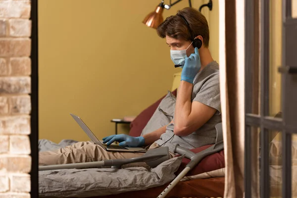 Selective Focus Freelancer Medical Mask Headset Using Laptop Crutches Bed — Stock Photo, Image