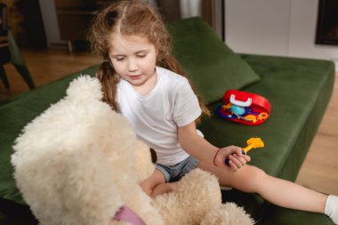 Doktorculuk oynarken oyuncak taşıyan sevimli çocuğun seçici odak noktası. 