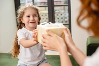selective focus of cute daughter giving present to mother clipart