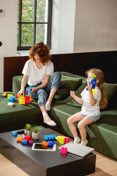 Cute Daughter Holding Water Gun Mother Gadgets Living Room — Stock Photo, Image