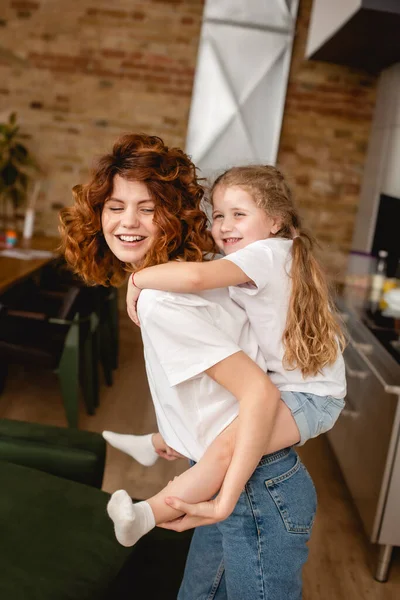 Positive Curly Mother Piggybacking Cute Daughter — Stock Photo, Image