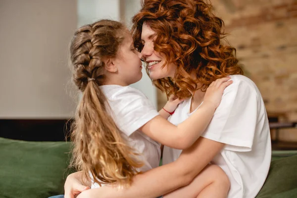 cute daughter hugging and touching noses with happy  mother