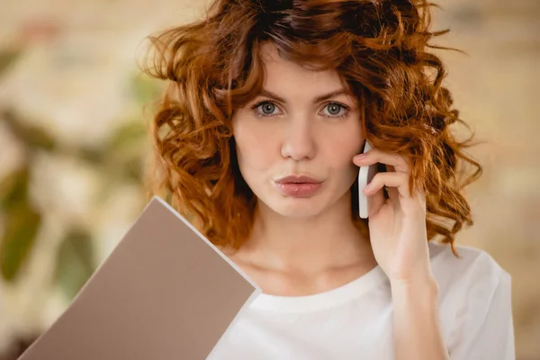 Kızıl Saçlı Kadın Klasörü Tutuyor Akıllı Telefondan Konuşuyor — Stok fotoğraf