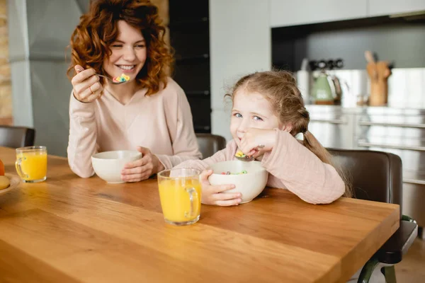 Cheerful Mother Daughter Holding Spoons Bowls Corn Flakes Glasses Orange — Stock Photo, Image