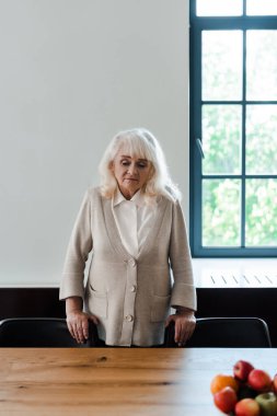 Yalnız, yaşlı bir kadın karantina sırasında meyveyle masada duruyor.