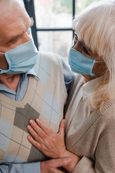 在检疫期间 一对戴着医疗面罩的快乐的老夫妇抱在家里 — 图库照片