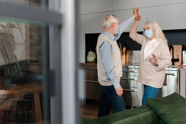 Ηλικιωμένο Ζευγάρι Ιατρικές Μάσκες Χορεύουν Στην Κουζίνα Κατά Διάρκεια Της — Φωτογραφία Αρχείου