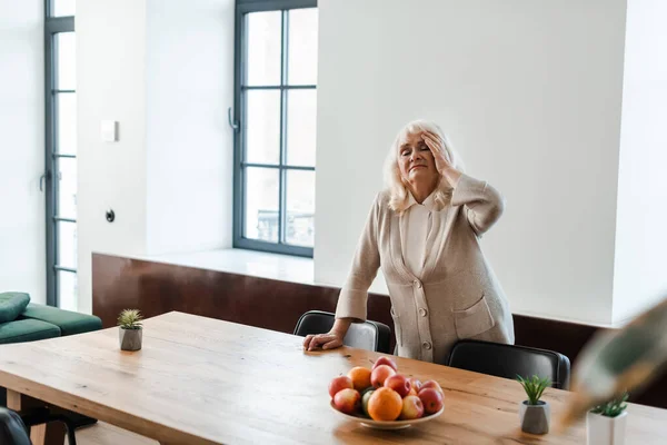 Seniorin Hat Kopfschmerzen Und Steht Während Der Selbstisolierung Mit Früchten — Stockfoto