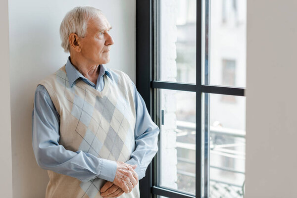 sad lonely man looking through window during quarantine