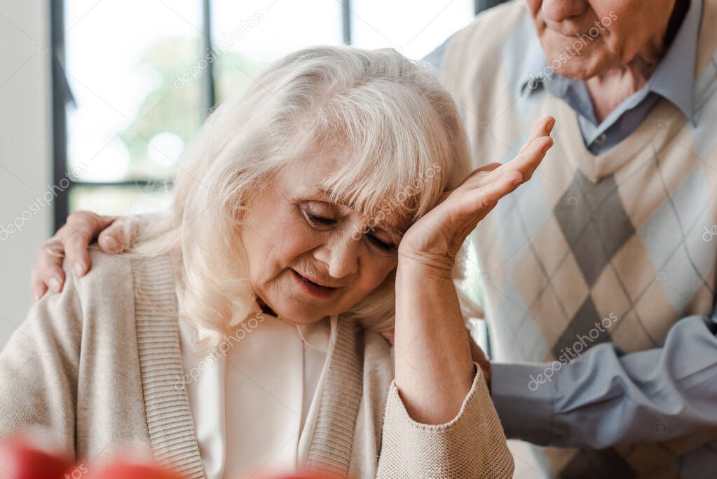 elderly wife having headache at home with husband during self isolation