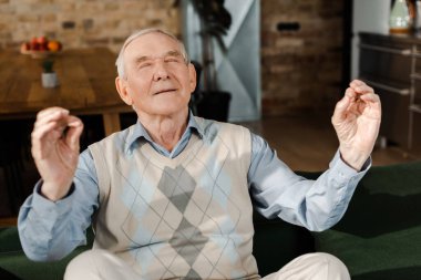 Karantina sırasında evde gözleri kapalı meditasyon yapan mutlu kıdemli adam.