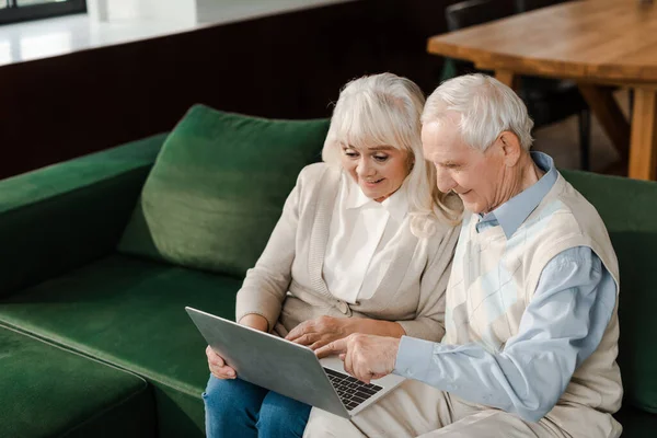 笑着的老夫妇在家里的笔记本电脑上进行视频聊天 — 图库照片