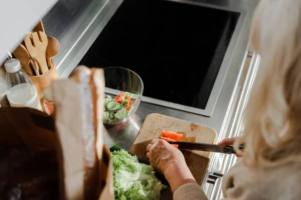 台所のサラダに乗って野菜を切る年配の女性の切り取りビュー — ストック写真