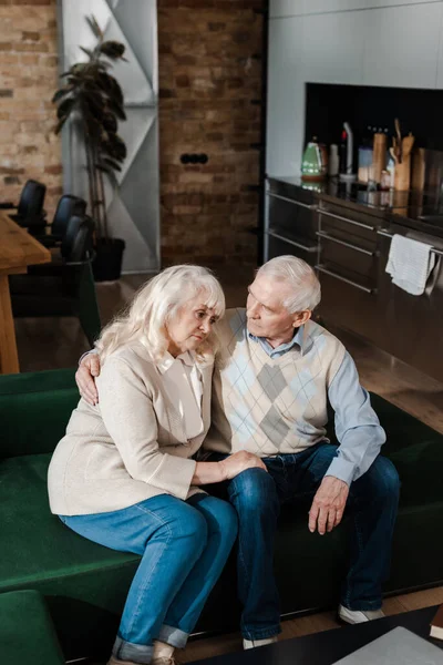 Θλιμμένη Ηλικιωμένη Σύζυγος Και Σύζυγος Αγκαλιασμένοι Και Καθισμένοι Στο Σπίτι — Φωτογραφία Αρχείου
