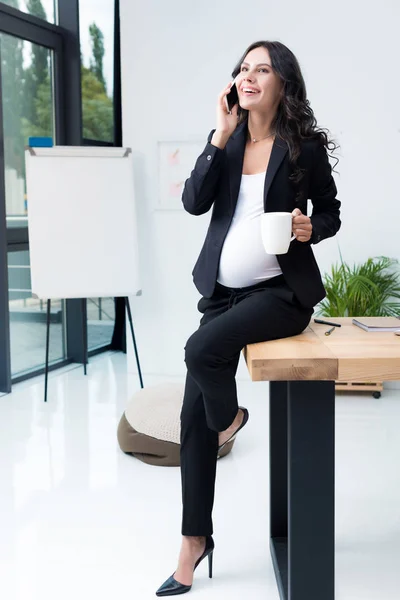 Pregnant businesswoman talking by phone — Stock Photo
