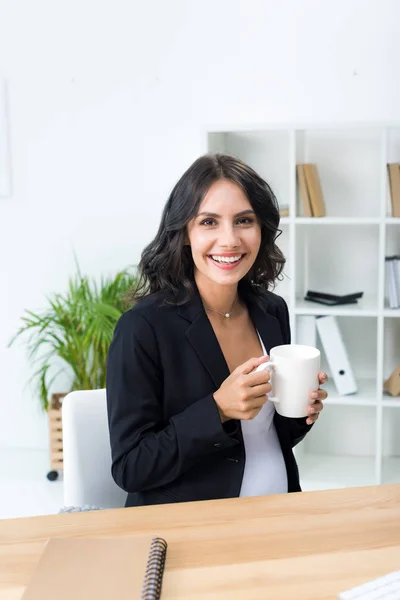 Pregnant businesswoman with cup of hot drink — Stock Photo