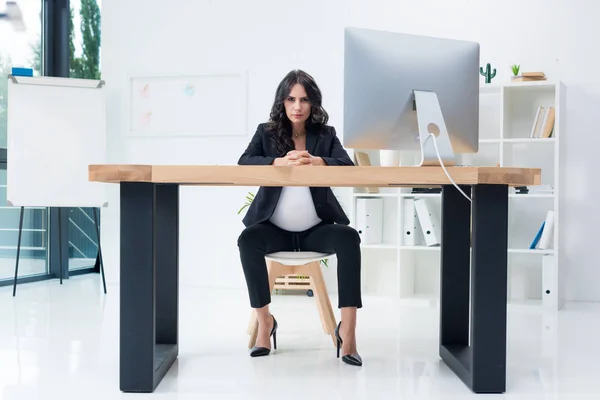 Serious pregnant businesswoman at workplace — Stock Photo